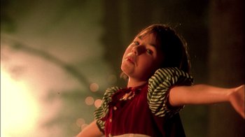 Movie still from “In Dreams” (1999), directed by Neil Jordan – A young girl in a red shirt is holding her arms up; Close Up shot, Low angle