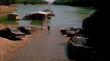 Movie still from “In Dreams” (1999), directed by Neil Jordan – A man walking down a road next to a body of water; Extreme Wide shot, High angle