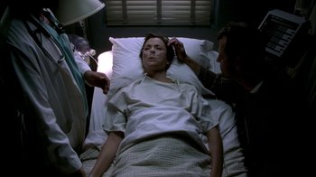 Movie still from “In Dreams” (1999), directed by Neil Jordan – A woman laying in a hospital bed with two men nearby; Medium shot, Over the shoulder angle