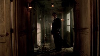 Movie still from “In Dreams” (1999), directed by Neil Jordan – A man standing in a hallway with a fire in it; Wide shot, Low angle