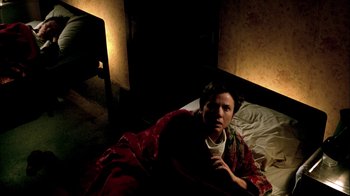 Movie still from “In Dreams” (1999), directed by Neil Jordan – A man laying in a bed with a red blanket; Medium shot, High angle