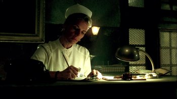 Movie still from “In Dreams” (1999), directed by Neil Jordan – A woman in a nurse's uniform writing on a paper; Medium shot, Low angle