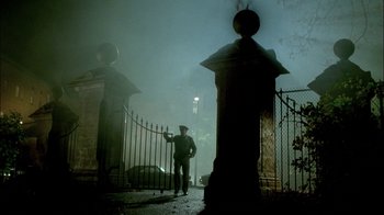 Movie still from “In Dreams” (1999), directed by Neil Jordan – A man standing in front of an iron gate; Wide shot, Low angle