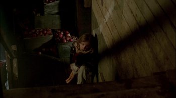 Movie still from “In Dreams” (1999), directed by Neil Jordan – A young girl sitting on a chair in a barn; Wide shot, High angle