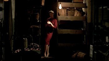Movie still from “In Dreams” (1999), directed by Neil Jordan – A woman in a red dress standing next to boxes; Wide shot, Low angle