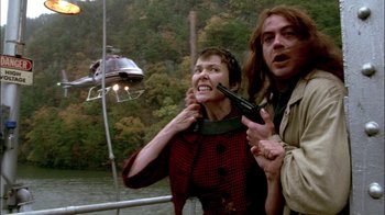 Movie still from “In Dreams” (1999), directed by Neil Jordan – A woman and a man are holding guns and a helicopter is in the background; Medium shot, Low angle