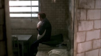 Movie still from “In Dreams” (1999), directed by Neil Jordan – A man sitting in a bathroom holding a pillow; Wide shot, High angle