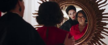 Movie still from “In Fabric” (2018), directed by Peter Strickland – A woman looking in the mirror in front of a mirror; Medium shot, Over the shoulder angle