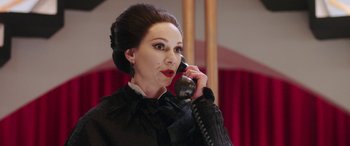 Movie still from “In Fabric” (2018), directed by Peter Strickland – A woman talking on a phone while wearing a black outfit; Close Up shot, Over the shoulder angle