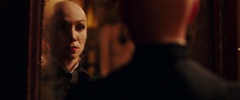 Movie still from “In Fabric” (2018), directed by Peter Strickland – A woman with a bald head is looking at the camera; Close Up shot, Over the shoulder angle
