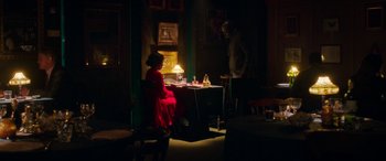 Movie still from “In Fabric” (2018), directed by Peter Strickland – A man and a woman sitting at a table in a dark room; Wide shot, Over the shoulder angle