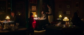 Movie still from “In Fabric” (2018), directed by Peter Strickland – A group of people sitting at a table in a room; Wide shot, Over the shoulder angle