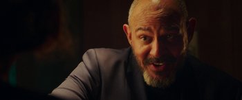 Movie still from “In Fabric” (2018), directed by Peter Strickland – A person with a beard; Close Up shot, Over the shoulder angle