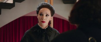 Movie still from “In Fabric” (2018), directed by Peter Strickland – A woman in a black dress with red lipstick; Close Up shot, Over the shoulder angle
