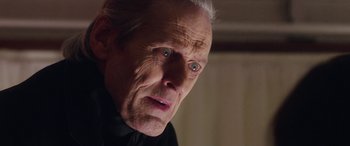 Movie still from “In Fabric” (2018), directed by Peter Strickland – An old man with a white beard looking at the camera; Close Up shot, Low angle