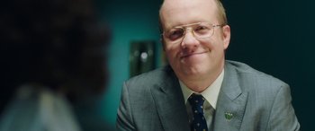 Movie still from “In Fabric” (2018), directed by Peter Strickland – A person wearing a suit and tie; Close Up shot, Over the shoulder angle