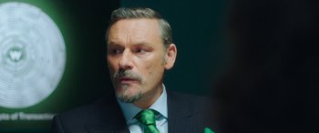 Movie still from “In Fabric” (2018), directed by Peter Strickland – A person wearing a suit and tie; Close Up shot, Over the shoulder angle