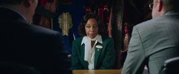 Movie still from “In Fabric” (2018), directed by Peter Strickland – A woman sitting at a table in front of a mirror; Medium shot, Over the shoulder angle