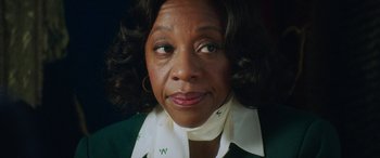 Movie still from “In Fabric” (2018), directed by Peter Strickland – An older black woman wearing a green and white shirt; Close Up shot, Low angle