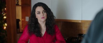 Movie still from “In Fabric” (2018), directed by Peter Strickland – A woman in a red shirt sitting in front of a white wall; Close Up shot, Over the shoulder angle