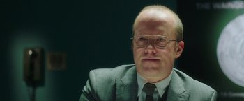 Movie still from “In Fabric” (2018), directed by Peter Strickland – An older man wearing a suit and tie; Close Up shot, Over the shoulder angle