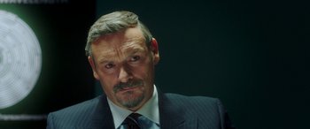 Movie still from “In Fabric” (2018), directed by Peter Strickland – A person wearing a suit and tie; Close Up shot, Over the shoulder angle