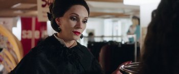 Movie still from “In Fabric” (2018), directed by Peter Strickland – A woman looking at a cell phone while wearing a black dress; Close Up shot, Over the shoulder angle