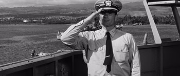 Movie still from “In Harm's Way” (1965), directed by Otto Preminger – A man saluting while standing on a boat in the water; Medium shot, Low angle