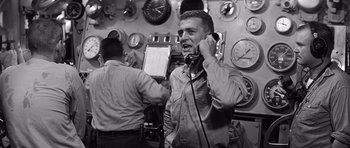 Movie still from “In Harm's Way” (1965), directed by Otto Preminger – A man talking on a phone while another man watches; Medium shot, Low angle