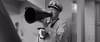 Movie still from “In Harm's Way” (1965), directed by Otto Preminger – A man in a sailor's hat is holding a megaphone; Medium shot, Low angle