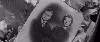 Movie still from “In Harm's Way” (1965), directed by Otto Preminger – An old black and white photo of a boy and a woman; Extreme Close Up shot, Overhead angle