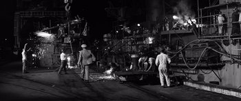 Movie still from “In Harm's Way” (1965), directed by Otto Preminger – A group of people standing on a street at night; Wide shot, High angle