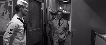 Movie still from “In Harm's Way” (1965), directed by Otto Preminger – A man in a suit and tie next to another man in a suit and tie; Medium shot, Low angle