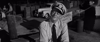 Movie still from “In Harm's Way” (1965), directed by Otto Preminger – An old photo of a man wearing a hat; Medium shot, Low angle