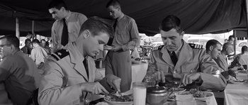 Movie still from “In Harm's Way” (1965), directed by Otto Preminger – A black and white photo of men eating food; Medium shot, High angle