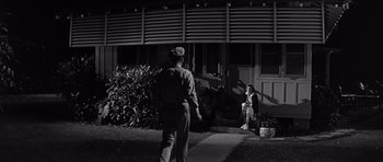 Movie still from “In Harm's Way” (1965), directed by Otto Preminger – A man and a woman standing in front of a house; Wide shot, Low angle