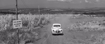 Movie still from “In Harm's Way” (1965), directed by Otto Preminger – An old car is driving down a dirt road; Extreme Wide shot, High angle