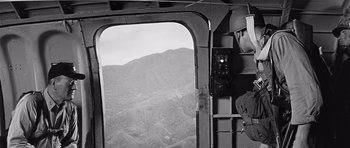 Movie still from “In Harm's Way” (1965), directed by Otto Preminger – A view of a mountain from inside of a helicopter; Wide shot, Low angle