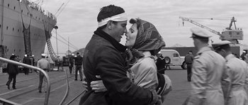 Movie still from “In Harm's Way” (1965), directed by Otto Preminger – A man and a woman are kissing on the side of the road; Medium shot, Low angle