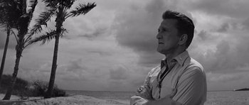 Movie still from “In Harm's Way” (1965), directed by Otto Preminger – A black and white photo of a man standing on the beach; Medium shot, Low angle