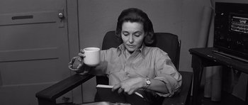 Movie still from “In Harm's Way” (1965), directed by Otto Preminger – A woman sitting in a chair holding a coffee mug; Medium shot, High angle