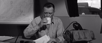Movie still from “In Harm's Way” (1965), directed by Otto Preminger – A black and white photo of a man drinking coffee; Medium shot, High angle
