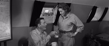 Movie still from “In Harm's Way” (1965), directed by Otto Preminger – An old photo of a man and a woman having a drink; Medium shot, Over the shoulder angle