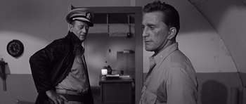 Movie still from “In Harm's Way” (1965), directed by Otto Preminger – A black and white photo of two men standing next to each other; Medium shot, Low angle
