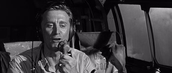 Movie still from “In Harm's Way” (1965), directed by Otto Preminger – A man with headphones on holding a wrench; Close Up shot, Low angle