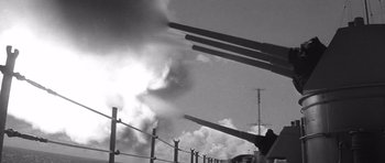 Movie still from “In Harm's Way” (1965), directed by Otto Preminger – A black - and - white photo of a gun range with smoke billowing out of it; Close Up shot, Low angle