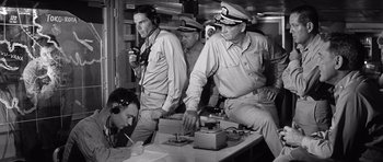 Movie still from “In Harm's Way” (1965), directed by Otto Preminger – A group of men standing next to each other on top of a table; Medium shot, High angle