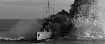 Movie still from “In Harm's Way” (1965), directed by Otto Preminger – A boat is in the water with smoke billowing out of it; Extreme Wide shot, Low angle