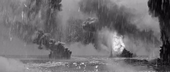 Movie still from “In Harm's Way” (1965), directed by Otto Preminger – A black - and - white photo of smoke billowing out of a forest; Extreme Wide shot, High angle