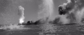 Movie still from “In Harm's Way” (1965), directed by Otto Preminger – An old photo of a boat in the water with smoke billowing out of it; Extreme Wide shot, High angle